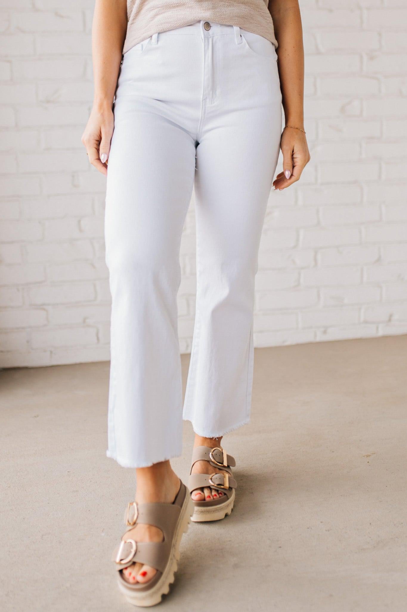 Woman wearing white cropped jeans with chunky tan sandals.