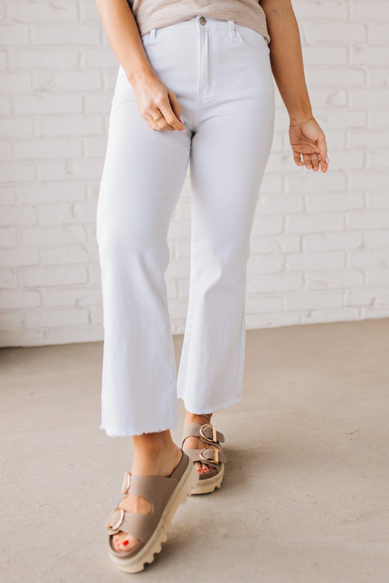 Woman wearing white cropped jeans with chunky tan sandals.