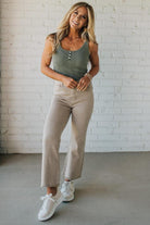 Blonde woman wearing ash mocha colored solid stretch jeans with mid rise and wide leg and a distressed hem accent.