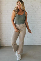 Blonde woman wearing ash mocha colored solid stretch jeans with mid rise and wide leg and a distressed hem accent.