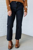 Person wearing black jeans and brown boots against a white brick wall.