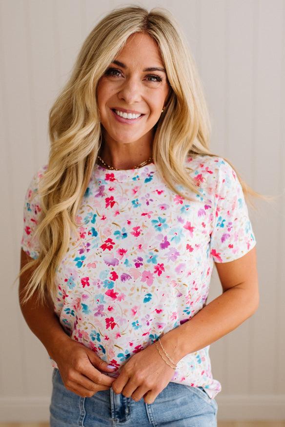 Woman wearing a colorful floral t-shirt against a neutral background
