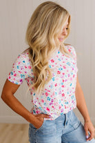 Woman wearing a floral top and jeans against a neutral background
