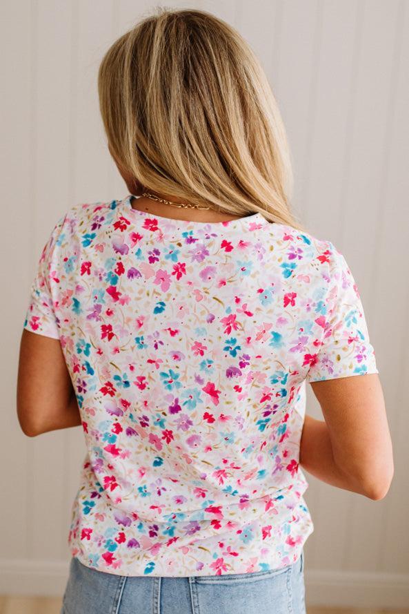 Person wearing a colorful floral-patterned shirt with a neutral background