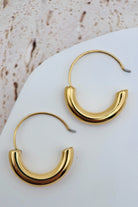 Gold hoop earrings on a white stone surface