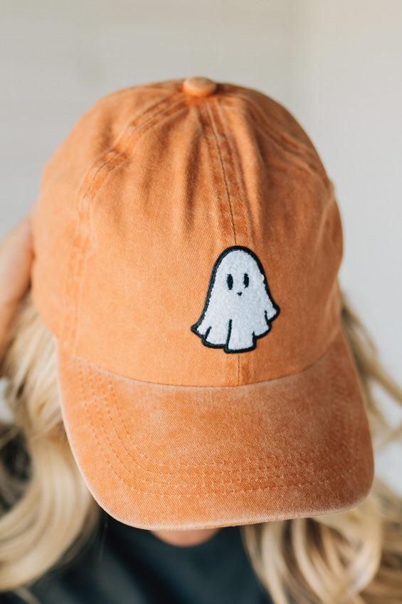 Orange cap with a ghost emoji on a blurred background