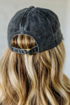 Black denim cap worn by a person with blonde hair against a neutral background