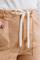 Close-up of tan pants with a white drawstring on a blurred background