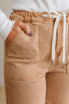 Close-up of brown jogger pants with a white drawstring on a neutral background