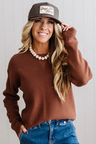 Blonde woman in a plaid hat wearing a solid waffle texture sweater with drop shoulder seams and crewneck.