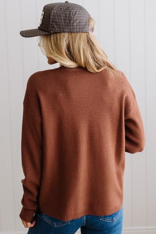Blonde woman in a plaid hat wearing a solid waffle texture sweater with drop shoulder seams and crewneck.