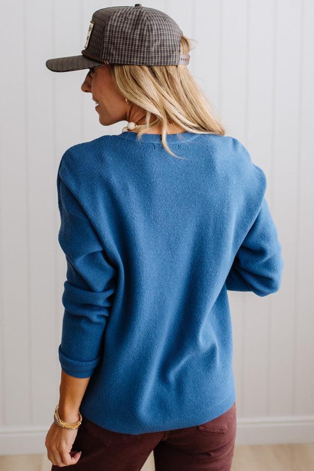 Blonde woman in a plaid hat wearing a solid waffle texture sweater with drop shoulder seams and crewneck.
