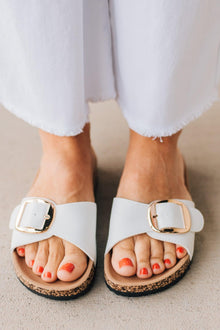  Cork sole sandals with white faux leather straps and gold buckle accent.