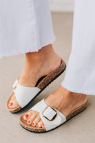 Cork sole sandals with white faux leather straps and gold buckle accent.