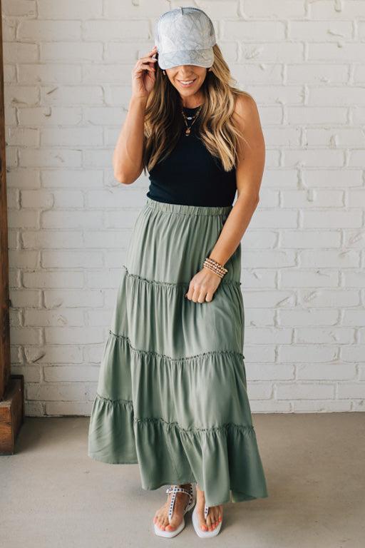 Blonde woman wearing a spruce green tiered rayon maxi skirt with elastic waistband.
