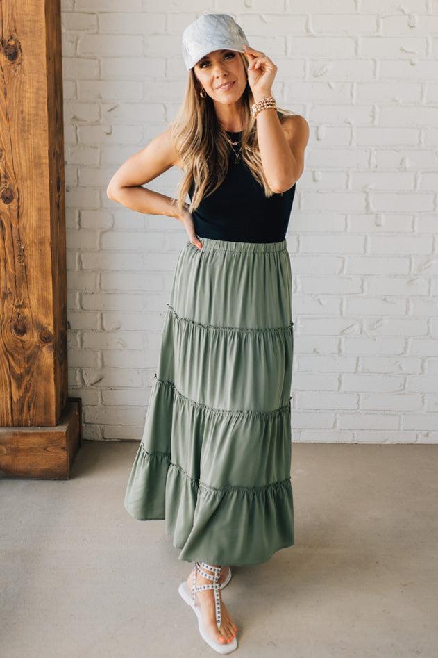 Blonde woman wearing a spruce green tiered rayon maxi skirt with elastic waistband.