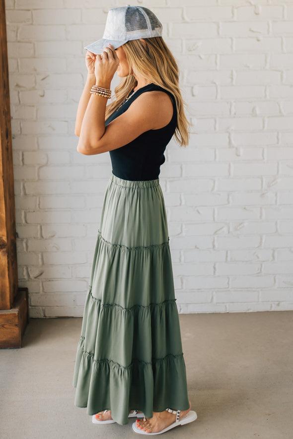 Blonde woman wearing a spruce green tiered rayon maxi skirt with elastic waistband.
