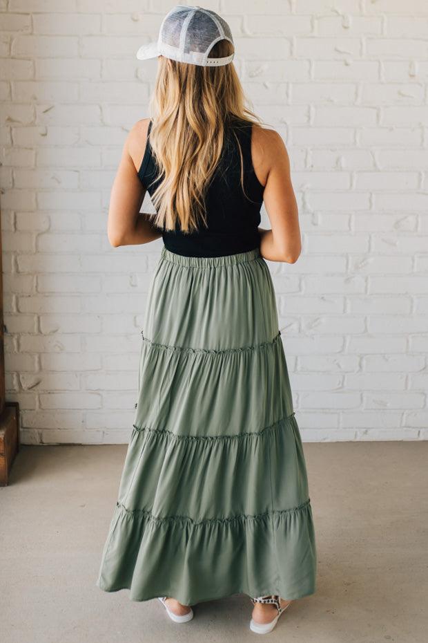 Blonde woman wearing a spruce green tiered rayon maxi skirt with elastic waistband.