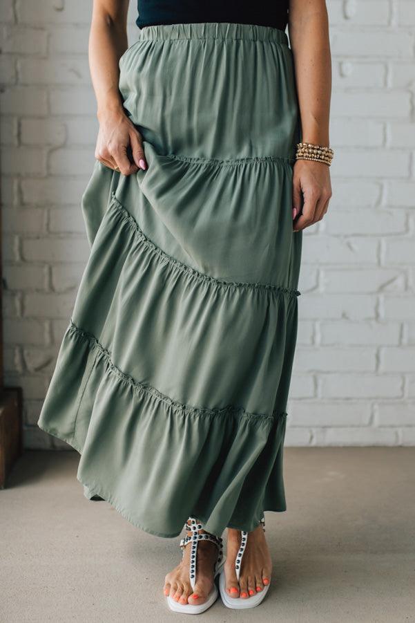 Blonde woman wearing a spruce green tiered rayon maxi skirt with elastic waistband.
