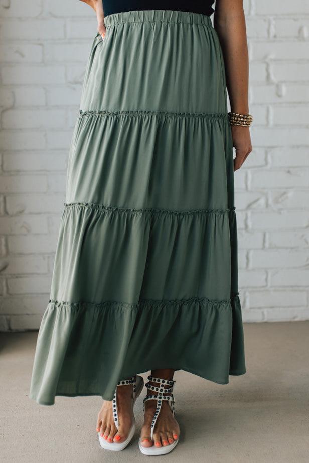 Blonde woman wearing a spruce green tiered rayon maxi skirt with elastic waistband.
