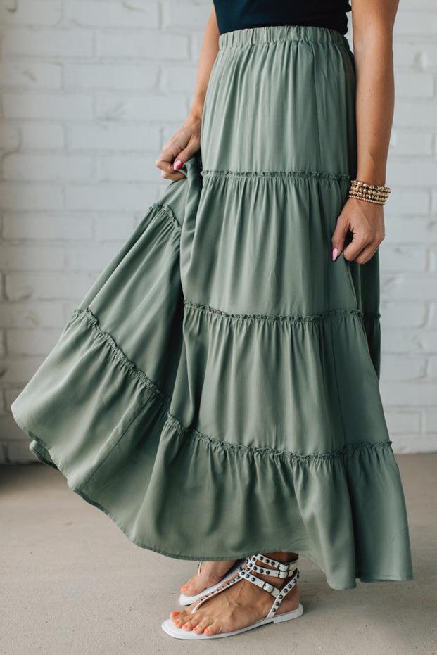 Blonde woman wearing a spruce green tiered rayon maxi skirt with elastic waistband.