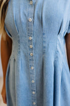 Light blue denim dress with buttons on a blurred background
