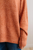 BLONDE WOMAN WEARING A HIGH-LOW HEM, LONG SLEEVE, SUPER SOFT, OVERSIZED CREW NECK SWEATER WITH RIB DETAILS AND STANDING IN A STUDIO WITH LIGHT WOOD FLOOR AND PANELED WALL BEHIND.