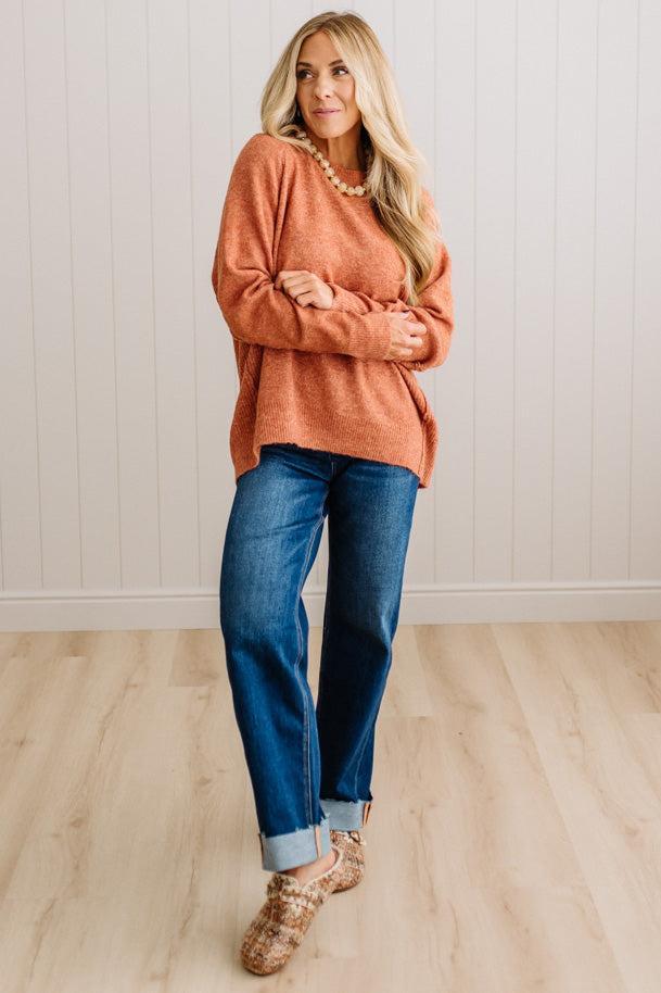 BLONDE WOMAN WEARING A HIGH-LOW HEM, LONG SLEEVE, SUPER SOFT, OVERSIZED CREW NECK SWEATER WITH RIB DETAILS AND STANDING IN A STUDIO WITH LIGHT WOOD FLOOR AND PANELED WALL BEHIND.