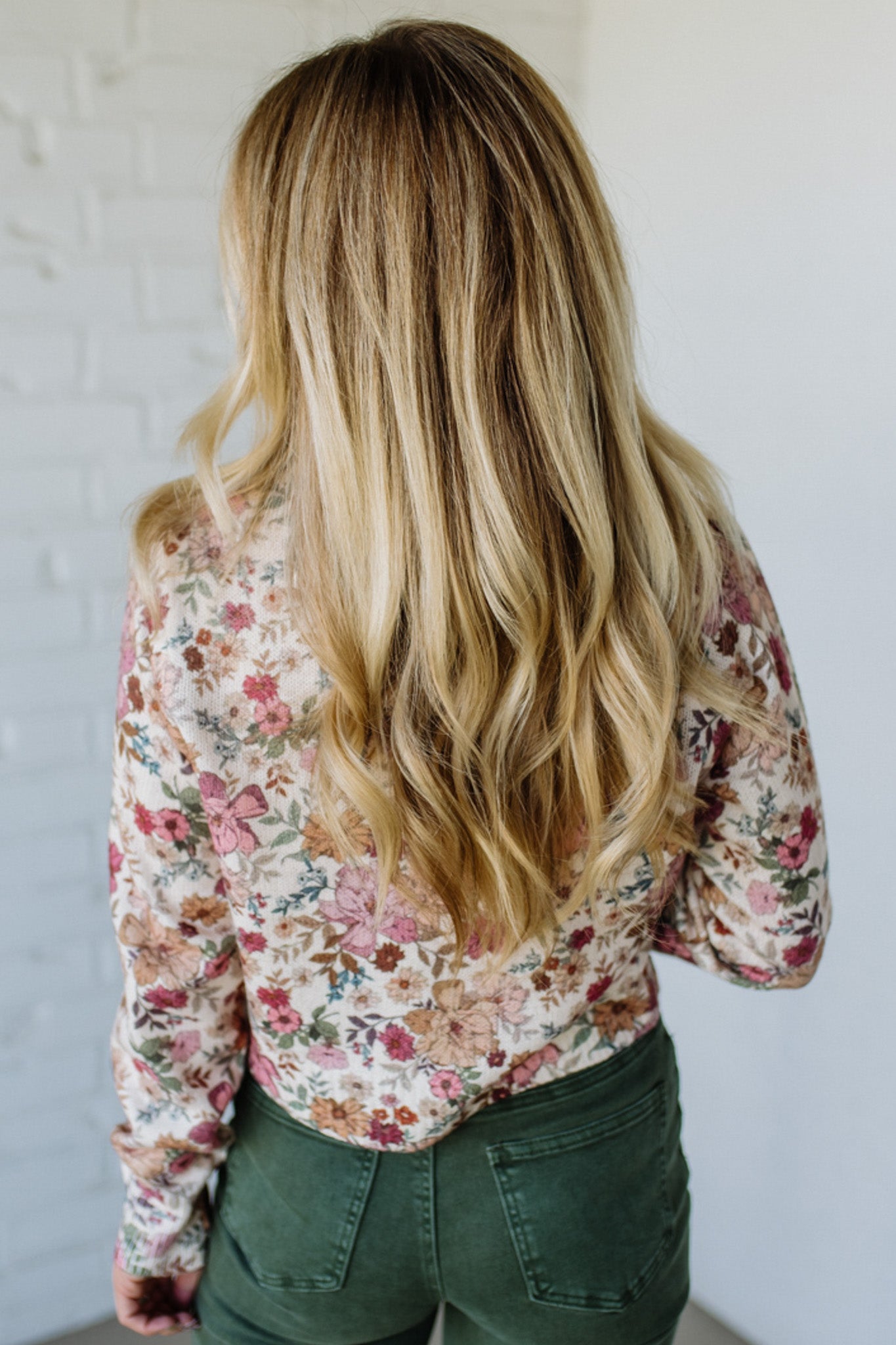 Woman wearing a floral shirt against a white brick wall