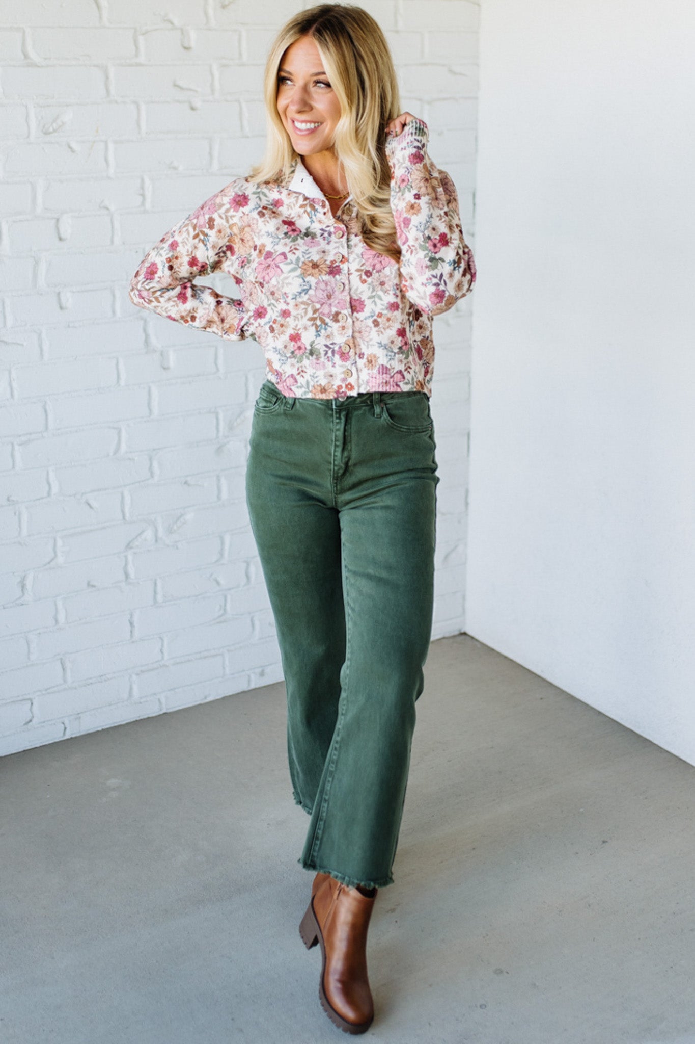 Woman wearing a floral shirt against a white brick wall