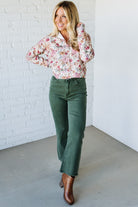 Woman wearing a floral shirt against a white brick wall