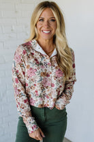 Woman wearing a floral shirt against a white brick wall