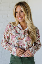 Woman wearing a floral shirt against a white brick wall