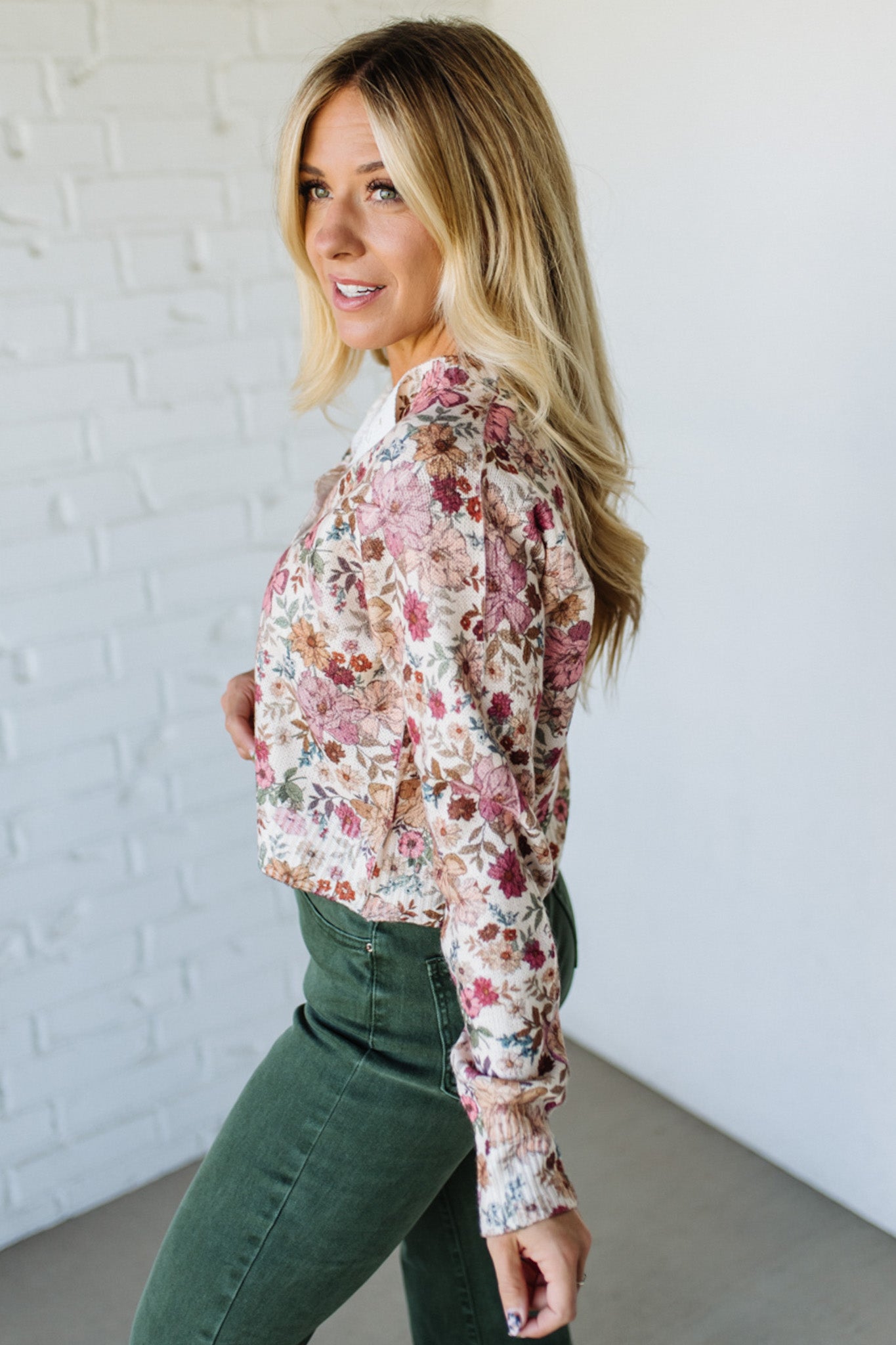 Woman wearing a floral shirt against a white brick wall