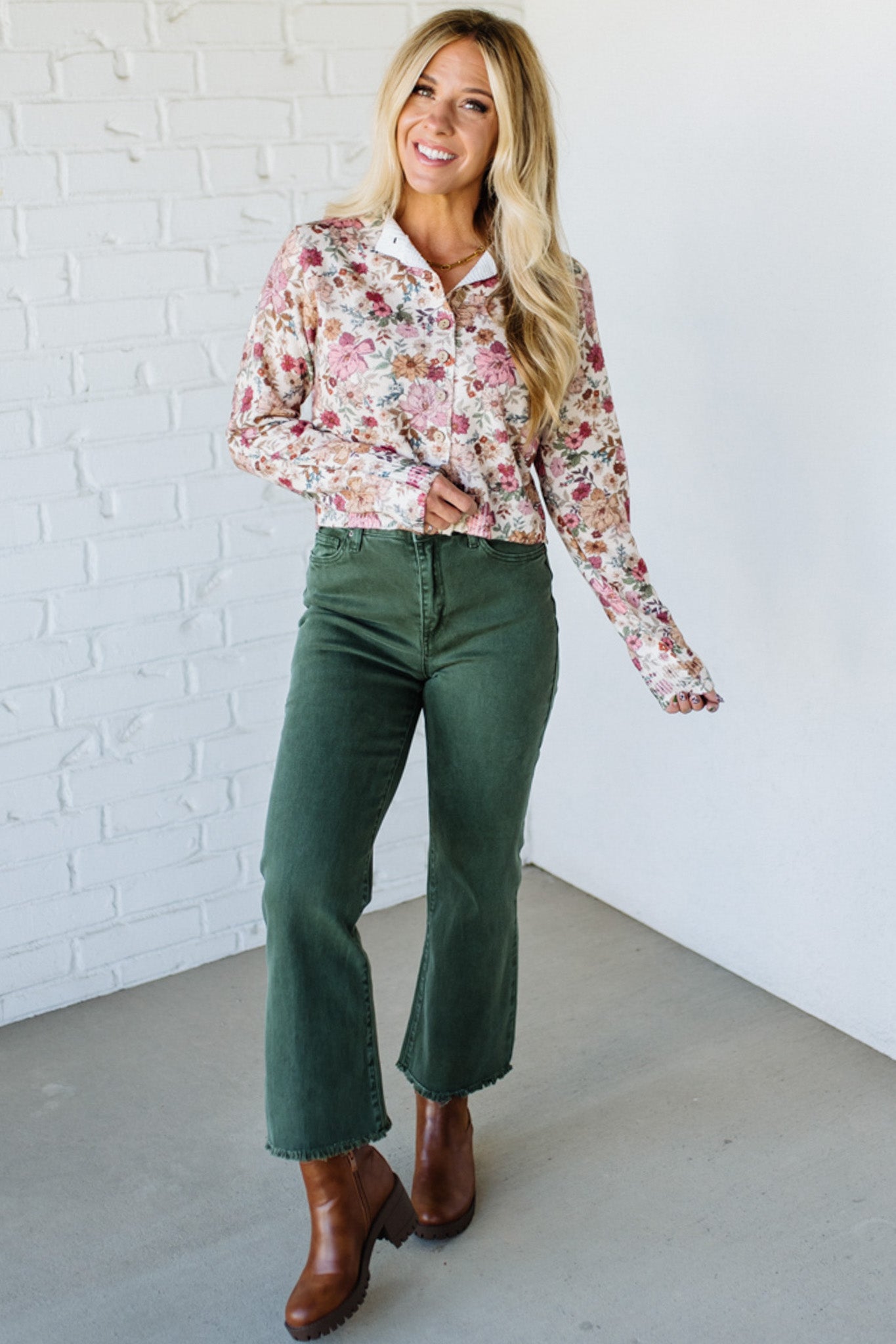 Woman wearing a floral shirt against a white brick wall
