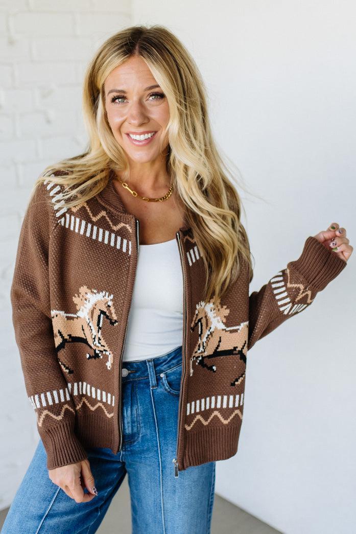 Woman wearing a brown cardigan with horse patterns against a white background