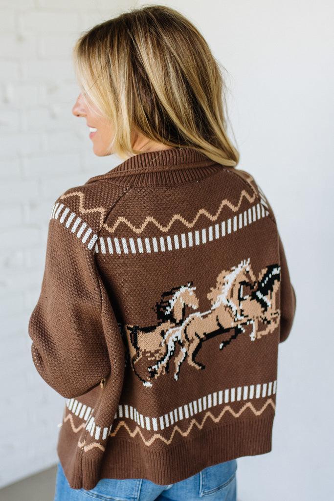 Woman wearing a brown sweater with horse designs against a white background