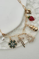 Gold necklace with various charms on a white plate
