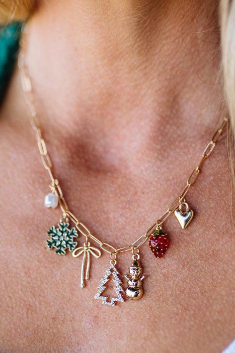 Necklace with various charms including a snowflake, bow, tree, and heart on a person's neck.