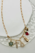 Gold necklace with various charms on a white plate