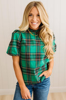 Woman wearing a green plaid top with ruffled sleeves against a neutral background