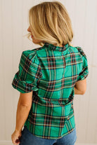 Woman wearing a green plaid shirt with puffed sleeves against a plain background
