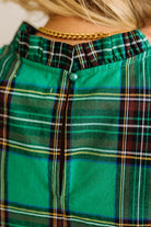Close-up of a green plaid shirt with a gold necklace.
