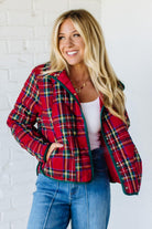 Woman wearing a red plaid jacket against a white brick wall