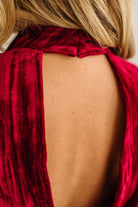 Close-up of a person wearing a red velvet garment with a halter neck design.