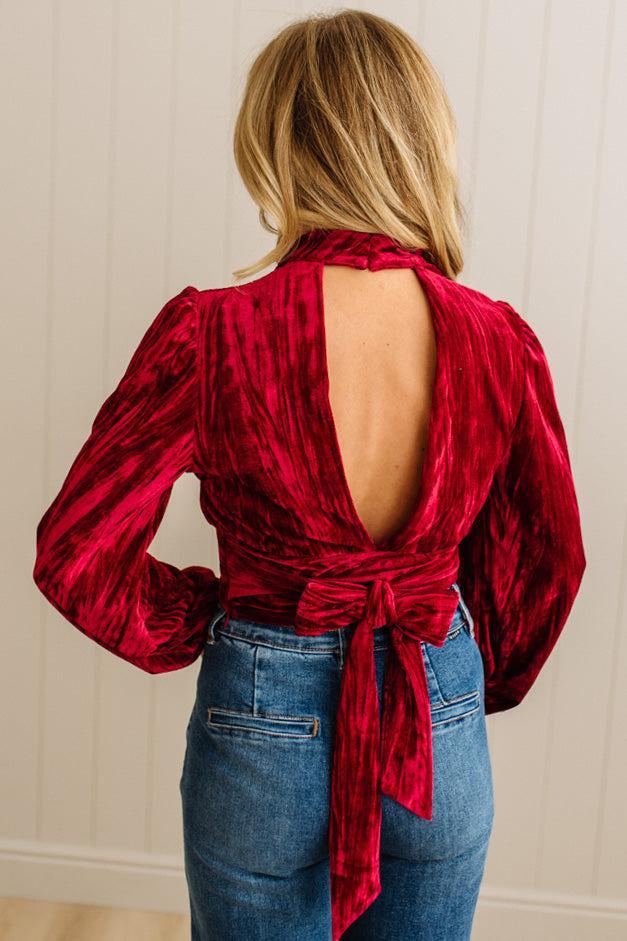Red velvet blouse with open back worn by a person against a neutral background