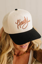 Person wearing a cap with 'Howdy' text on a neutral background