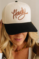 Person wearing a cap with 'Howdy' embroidery on a neutral background