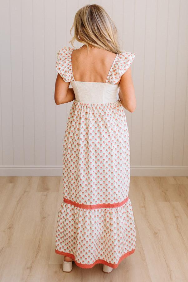 Woman wearing a long, patterned dress with a white background