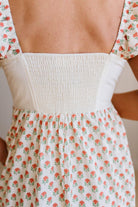 Close-up of a floral dress with a white top and red floral pattern.